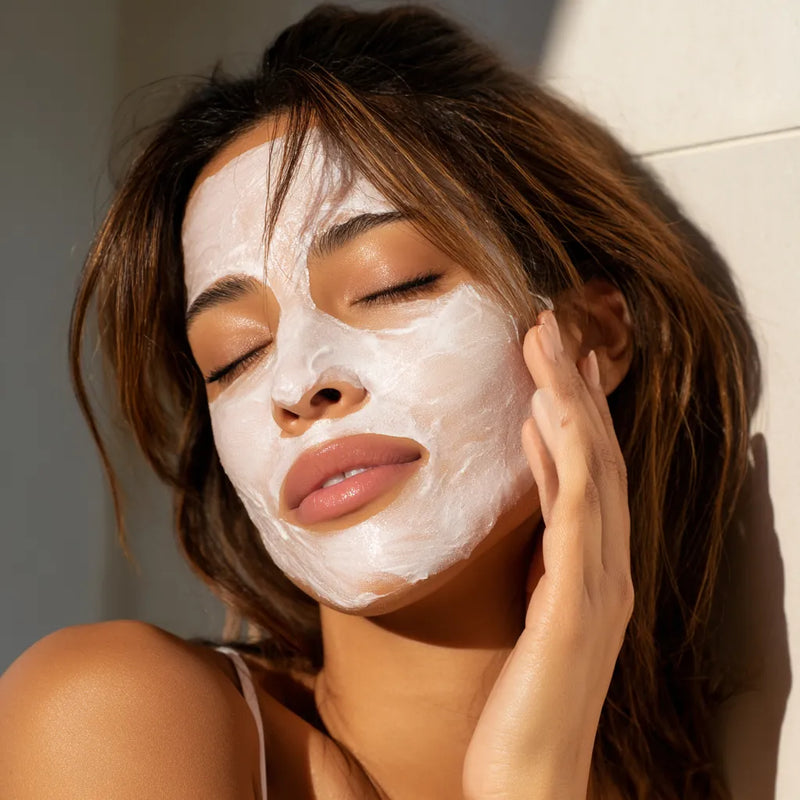 Femme très belle appliquant un masque hydratant transparent sur sa joue, texture gel fraîche visible, dans une ambiance spa douce et lumineuse. collection