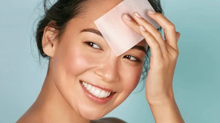 Femme souriante utilisant un papier absorbant pour maintenir l'équilibre d'une peau normale avec une routine K-Beauty