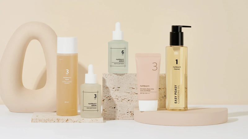 un 0 a gauche beige de produit sur ca droite sur du marbres devant un fond beige ambiance coréenne très subtile le tout très élégant  collection
